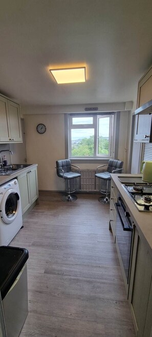 Una cocina compacta con lavadora, estufa y ventana con vistas.