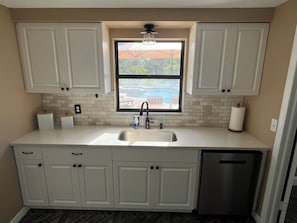 A kitchen with white cabinets, a stainless steel sink, and a window overlooking a pool.