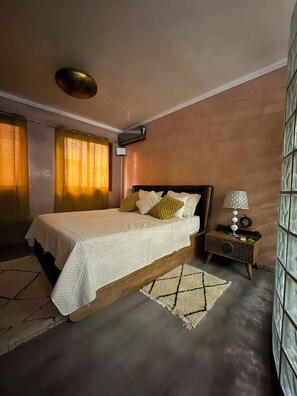 A bedroom with a bed, bedside table, lamp, and a large window. - Stunning, Cozy, and Modern Duplex – 5 min from the Airport & 15 min from Downtown (Marrakech)