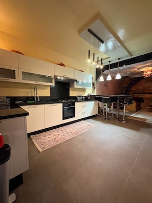 A modern kitchen with white cabinets, a black countertop, and hanging pendant lights. - Stunning, Cozy, and Modern Duplex – 5 min from the Airport & 15 min from Downtown (Marrakech)