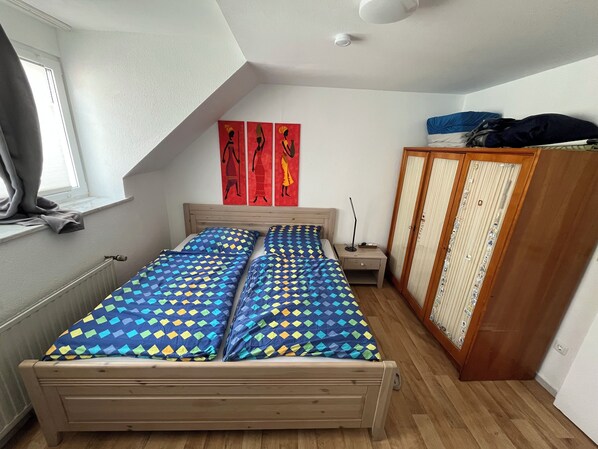 A bedroom with a bed, a wardrobe, and a window.