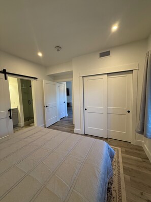 A bedroom with a large bed, two closets, and a bathroom with a shower. - New build 2-bedroom 2 Bath condo with AC in welcoming Bozeman (Bozeman)