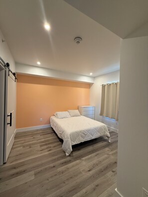 A bedroom with a bed, a bedside table, a wardrobe, and a window with curtains. - New build 2-bedroom 2 Bath condo with AC in welcoming Bozeman (Bozeman)
