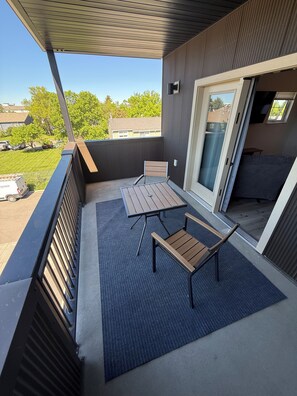 An outdoor balcony with a table and chairs, a sliding glass door, and a view of the neighborhood. - New build 2-bedroom 2 Bath condo with AC in welcoming Bozeman (Bozeman)