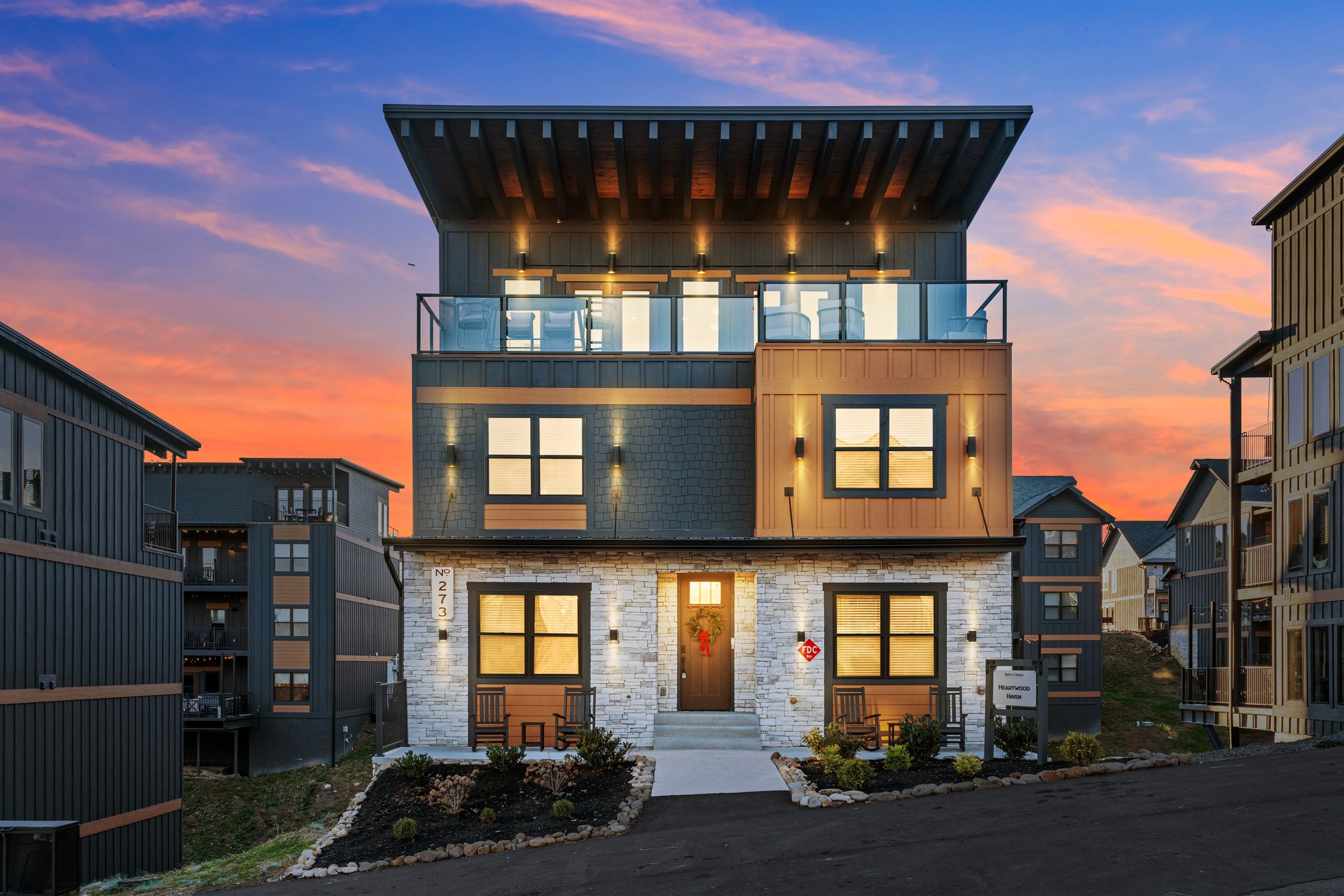 A modern two-story building with a stone facade, large windows, and a balcony.