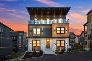 Een modern, tweelaags gebouw met een gevel van natuursteen, grote ramen en een balkon.