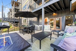 Een buitenpatio met een eettafel, stoelen, een vuurplaats en een bank.