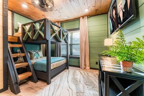 Ein Stockbett mit einer Leiter, ein Nachttisch mit einer Lampe und ein Blumentopf.