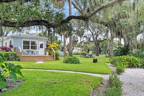 A small house with a porch, surrounded by a well-maintained lawn and trees.