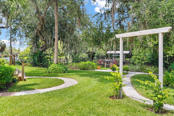 A well-maintained garden with a wooden pergola, a winding gravel path, and a variety of greenery.