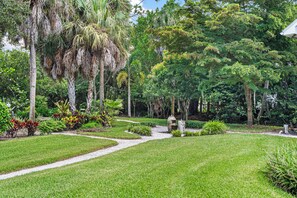 Un jardín bien cuidado con una variedad de plantas y árboles, un sendero despejado y una estructura de piedra decorativa.