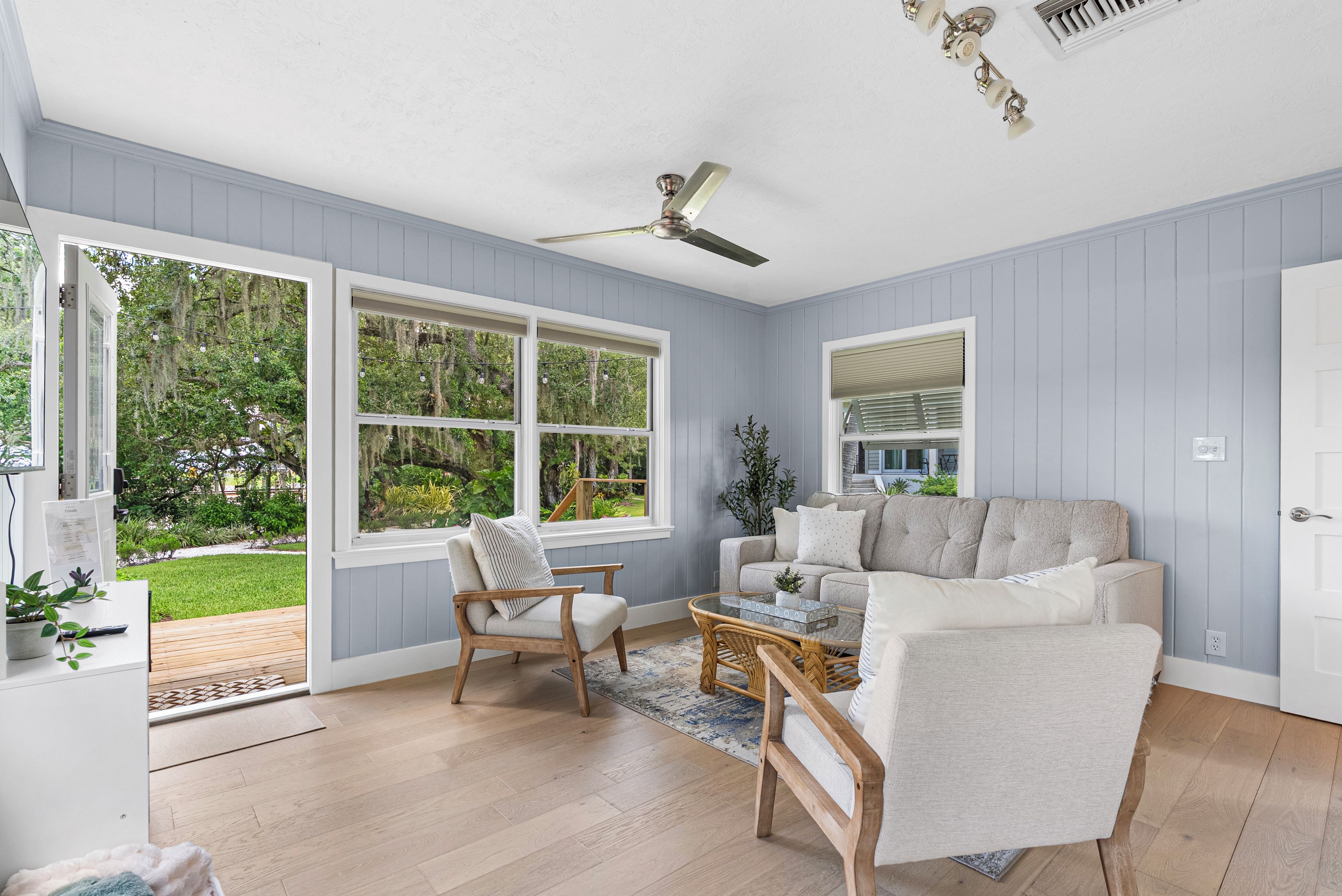 A room with a large window, a ceiling fan, and a light fixture.