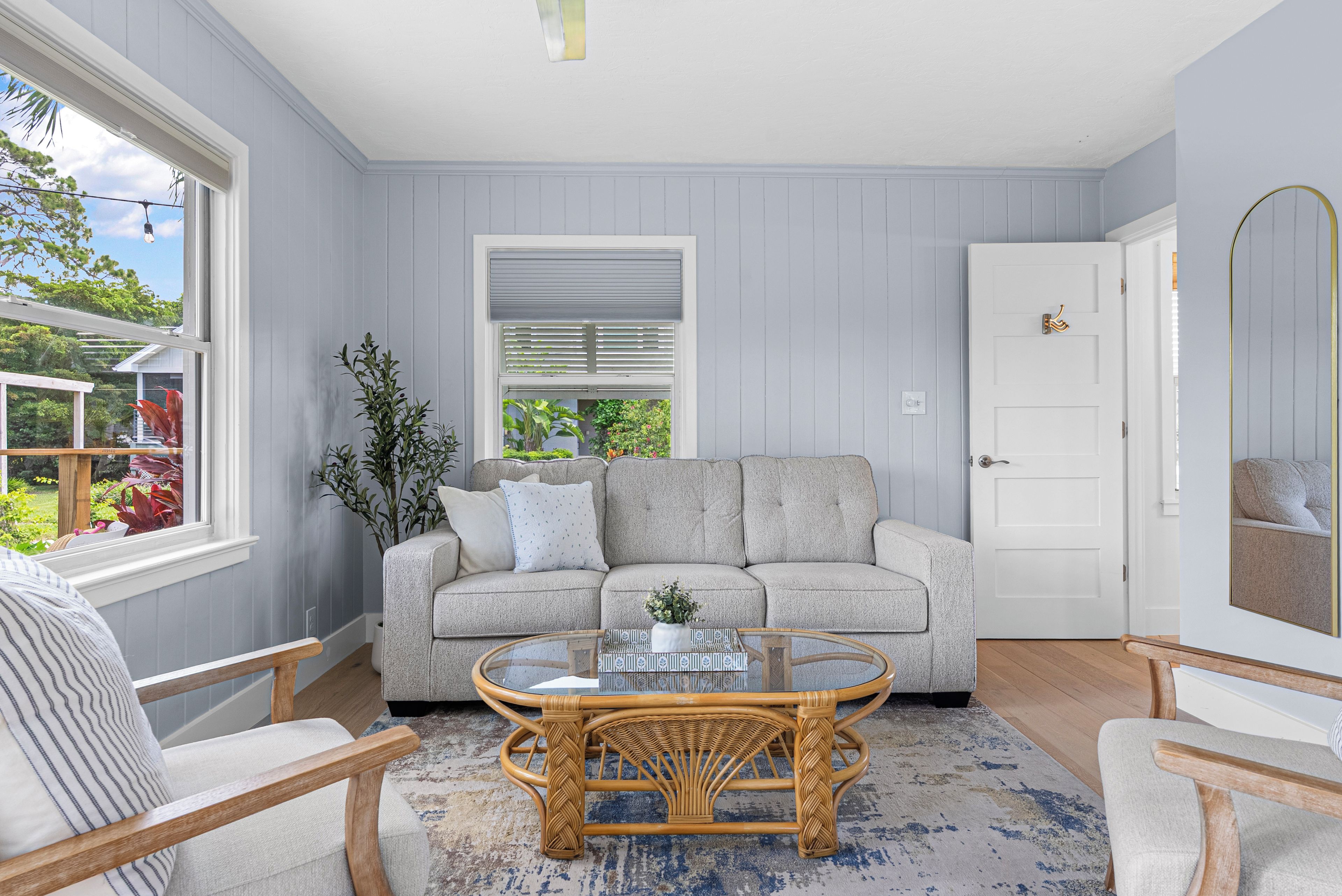 A room with a grey sofa, a wicker coffee table, and a white door.