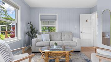 A room with a grey sofa, a wicker coffee table, and a white door.