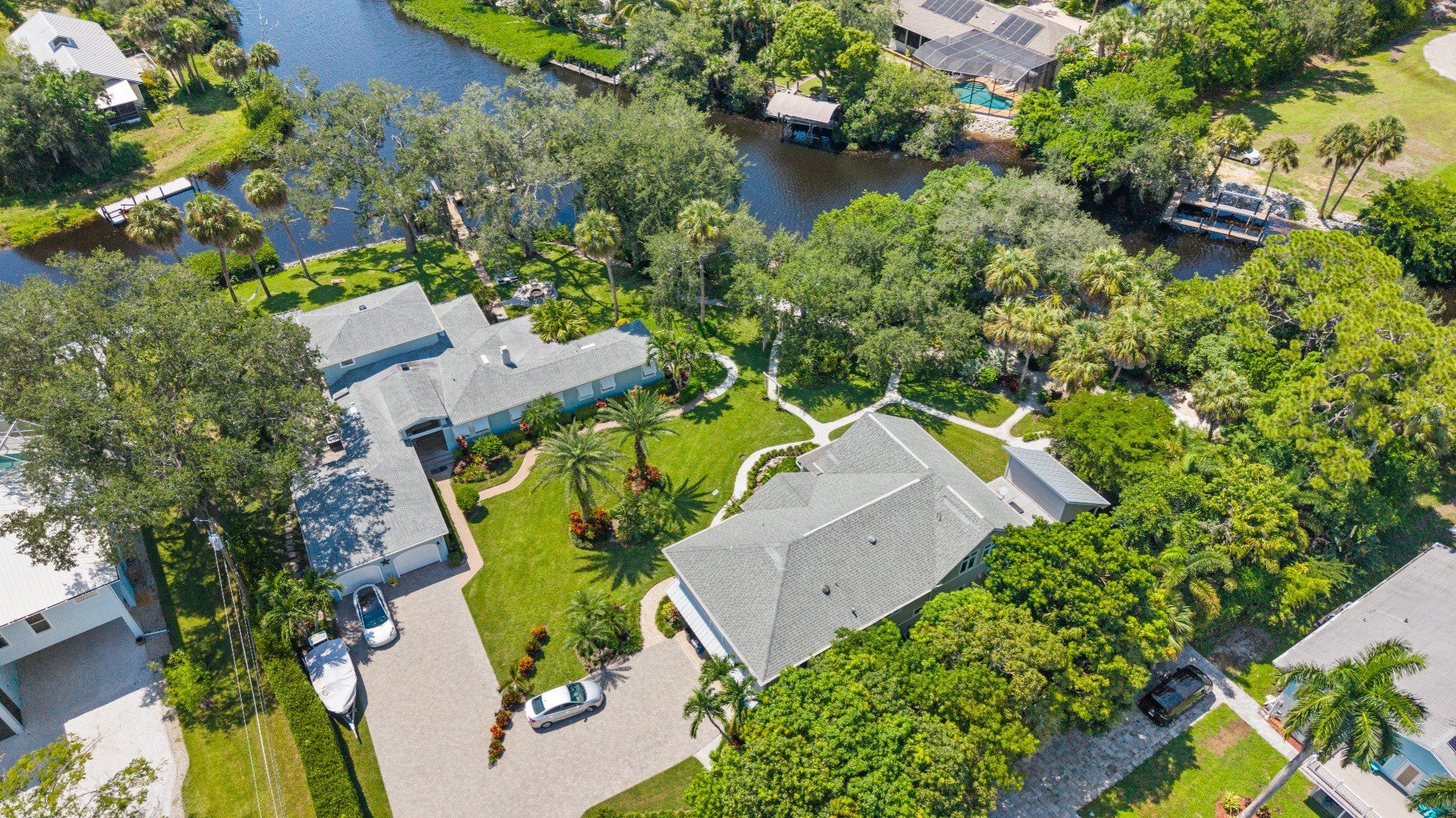 An aerial view of a residential area with houses, a river, and a boat dock.