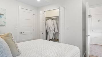 Een slaapkamer met een bed, een kast met daarin een badjas en een deur naar een andere kamer.