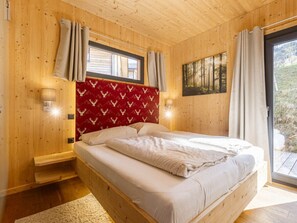 Ein Schlafzimmer mit Holzwandverkleidung, einem Bett, zwei Wandleuchten und einem Fenster mit Vorhängen.