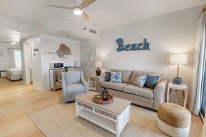 Ein modernes Wohnzimmer mit Sofa, Sessel, Couchtisch und einem an der Wand befestigten Schild mit der Aufschrift 'Beach'.