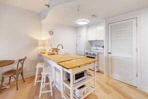 A compact kitchen with a wooden island, white cabinetry, a built-in oven, and a small dining area with stools. - The View at Carillon - Lake & Gulf Views + Resort Amenities (Panama City Beach)