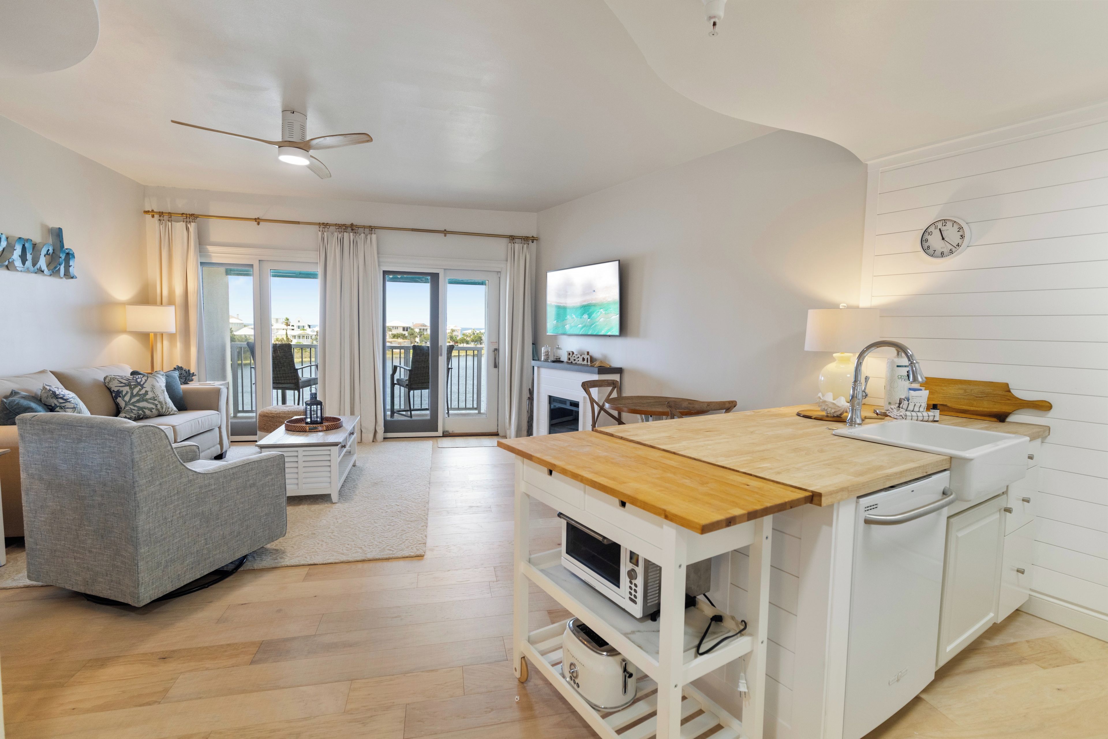 A modern living room with a sofa, a dining table, and a kitchen area with a sink and microwave.