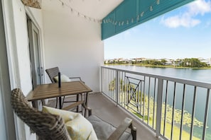 Ein Balkon mit Tisch und Stühlen, der auf ein Gewässer mit Blick auf Häuser in der Ferne blickt.