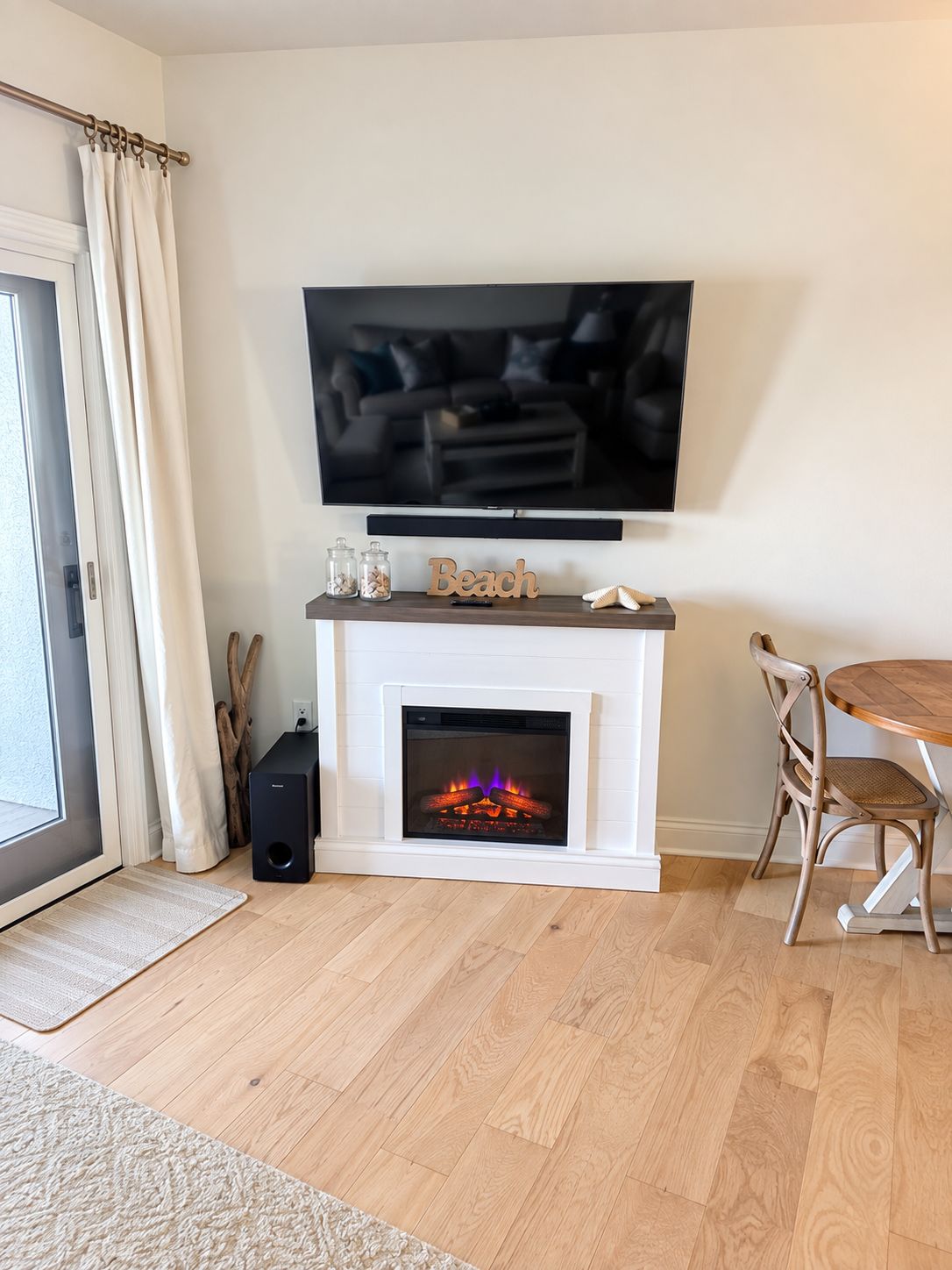 Una sala de estar con chimenea, un televisor montado sobre ella y un comedor con mesa y sillas de madera.