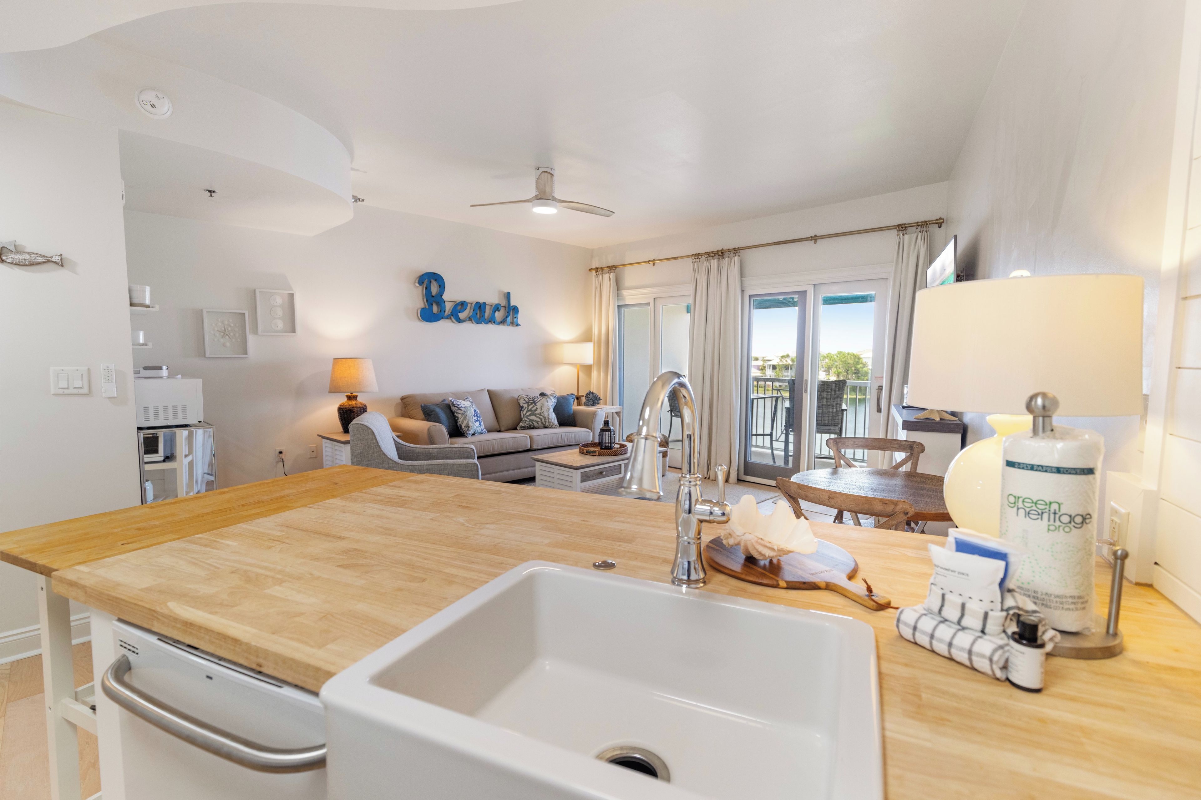 Spacious open-concept living with a fully equipped kitchen island, perfect for preparing meals while staying connected to your group. Natural light fills the room, leading your eye to the balcony and outdoor views.