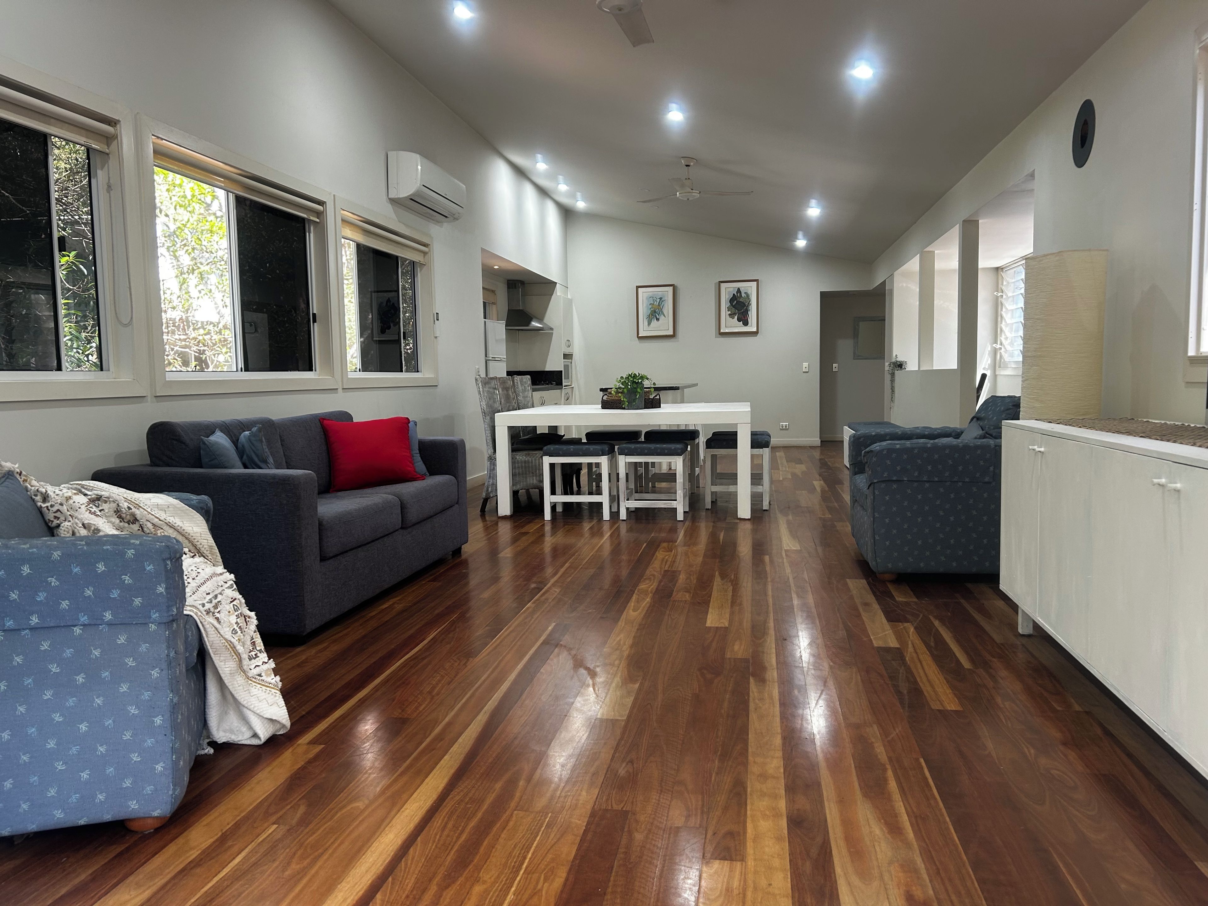 A modern living space with a dining area, kitchen, and seating arrangements.
