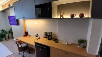 A compact kitchen with a microwave, coffee maker, and a small refrigerator.