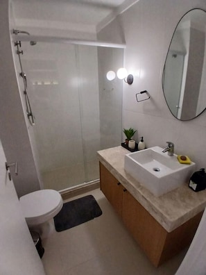 Casa de banho moderna com chuveiro, sanita e toucador.