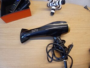 A black hairdryer with a cord on a wooden surface. - SHB - 200m Praia Studio Moderno Gonzaga (Santos)