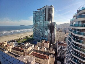 Un edificio de gran altura con fachada curva, junto a una playa y otros edificios residenciales.