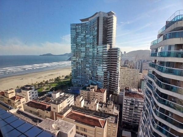 Un edificio de gran altura con fachada curva, junto a una playa y otros edificios residenciales.