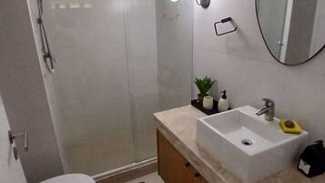 Un baño moderno con ducha, inodoro, lavabo y espejo.