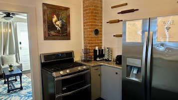 Cocina compacta con estufa, horno, refrigerador y cafetera.