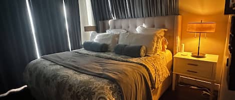 A bedroom with a large bed, a bedside table with a lamp, and a ceiling fan.