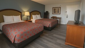 Habitación de hotel con dos camas, un televisor, una mesita y una puerta.