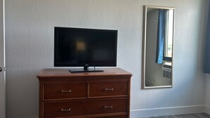 Una habitación con un aparador de madera, un televisor de pantalla plana encima y un espejo en la pared.
