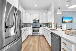A modern kitchen with stainless steel appliances, white cabinetry, and a wooden floor. - Good Day Sunshine by Stay on 30a (Seacrest Beach)