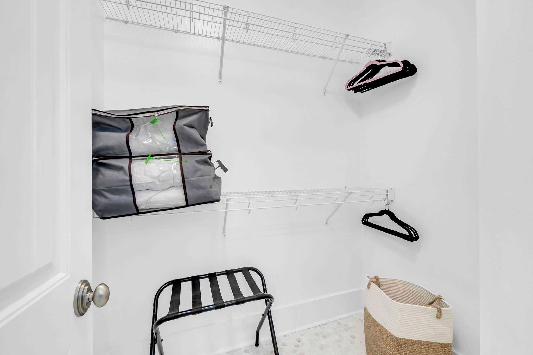 A white room with a drying rack, a storage bag, a hanging rack, and a basket.