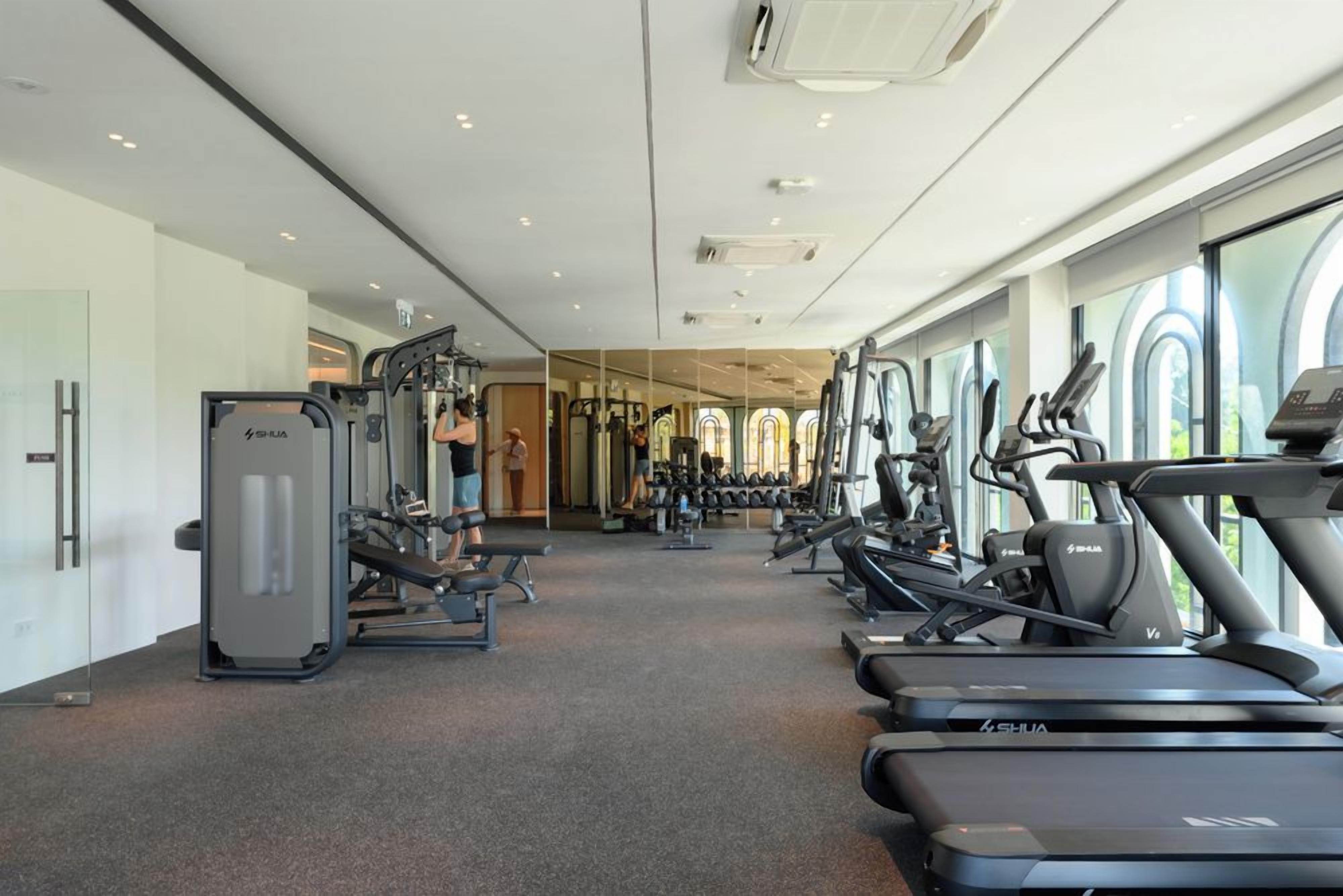Ein Fitnessraum mit Cardiogeräten, Krafttrainingsgeräten und einer Spiegelwand.