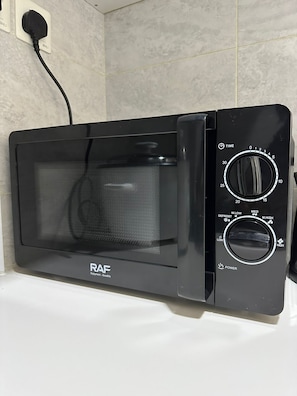 A black microwave oven with a digital timer and power settings, placed on a white countertop.