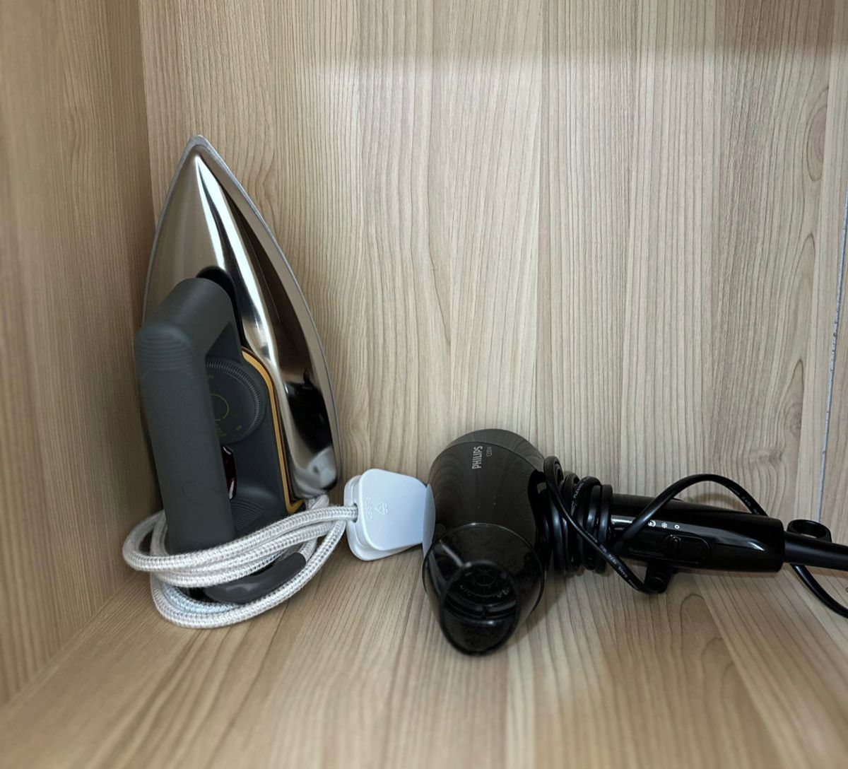 A wooden cabinet with an iron and a power adapter inside.