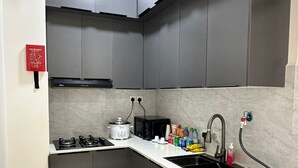Eine kleine Küche mit grauen Schränken, einem Gasherd, einer Mikrowelle, einem Spülbecken und einer Waschmaschine.