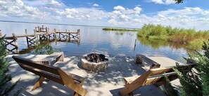 A lakeside deck with wooden benches and a fire pit.