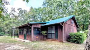 Un rustico chalet con tetto verde, un portico e una piccola terrazza.