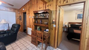 Una stanza con rivestimento in legno, un tavolo da lavoro, una sedia e un letto.