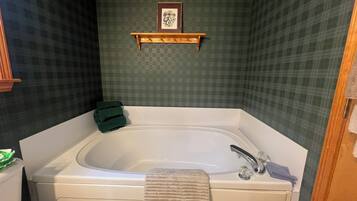A bathroom with a bathtub, a toilet, and a shower area.