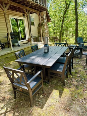 An outdoor wooden deck with a picnic table and chairs, surrounded by trees. - Carter Creek Retreat - Ride to trails! (Mena)