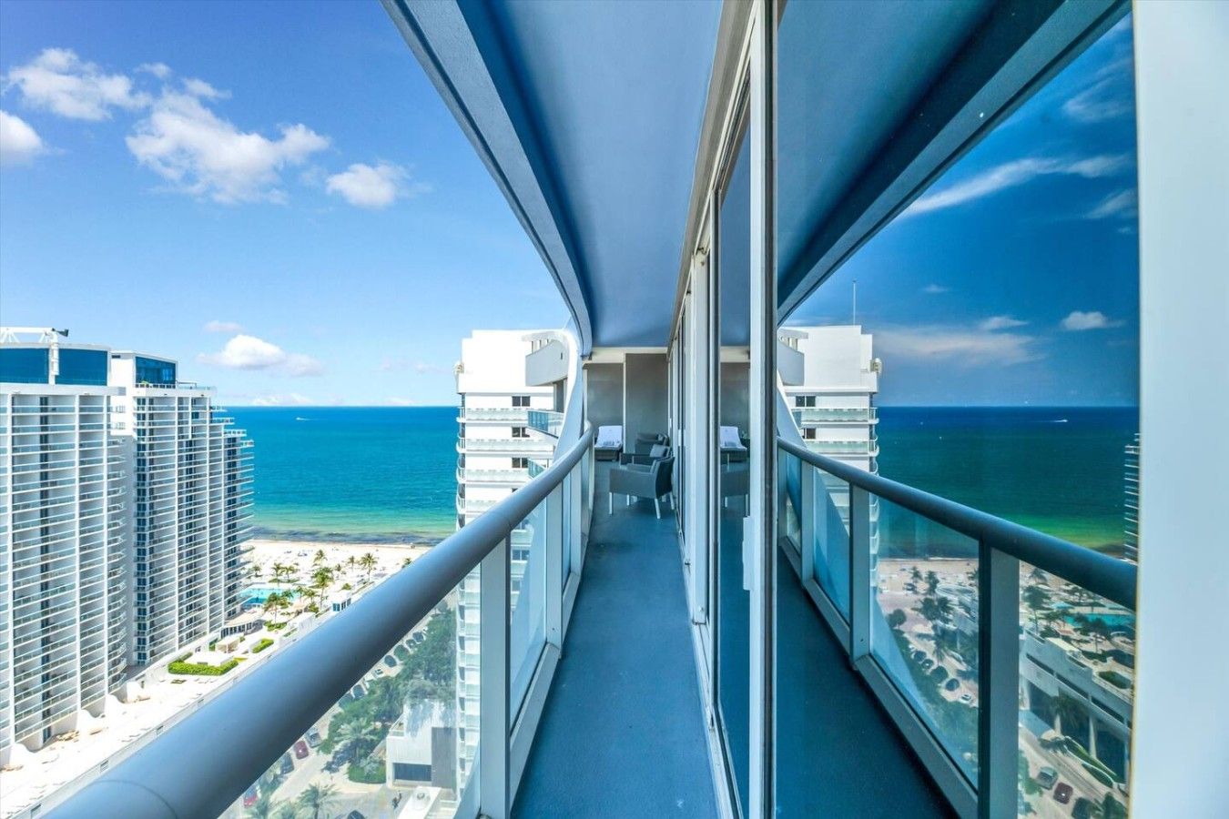 Ein schmaler Balkon mit Blick auf das Meer und hohe Gebäude.